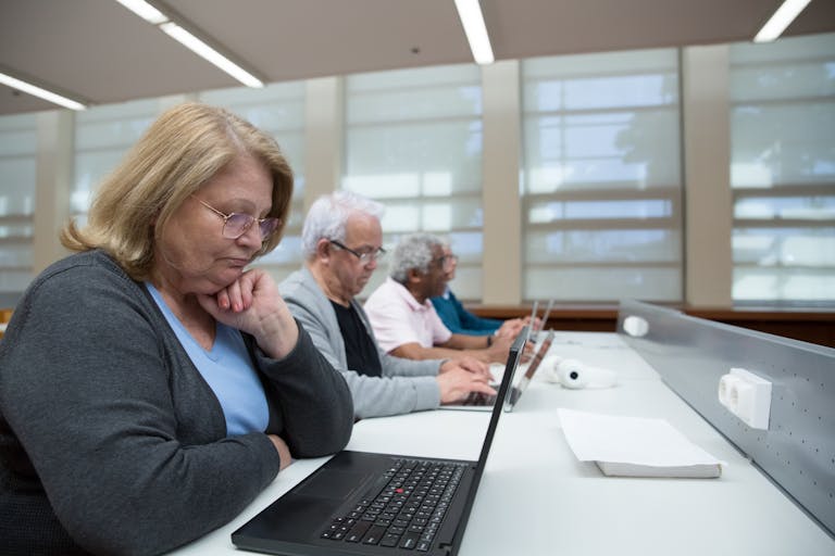 Seniors engaged in a computer class, learning digital skills with laptops indoors.